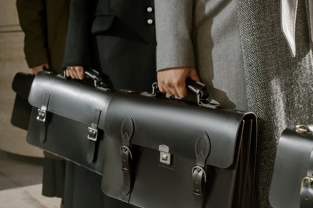 about-01 Group of adults holding sleek leather briefcases in formal business attire, emphasizing corporate professionalism.